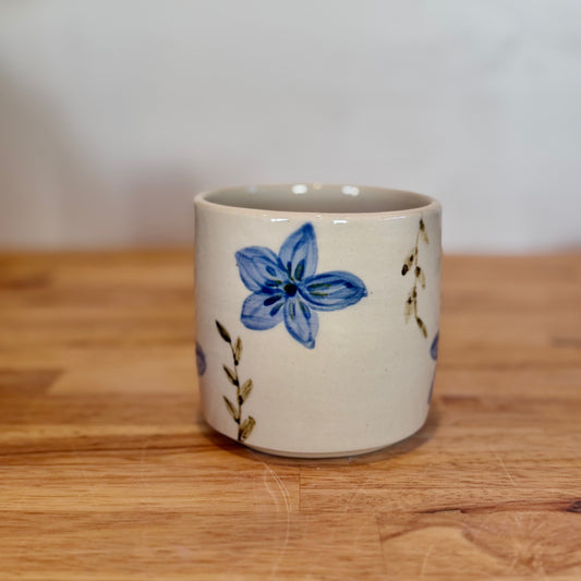 Ceramic mug with a blue floral design on a wooden surface