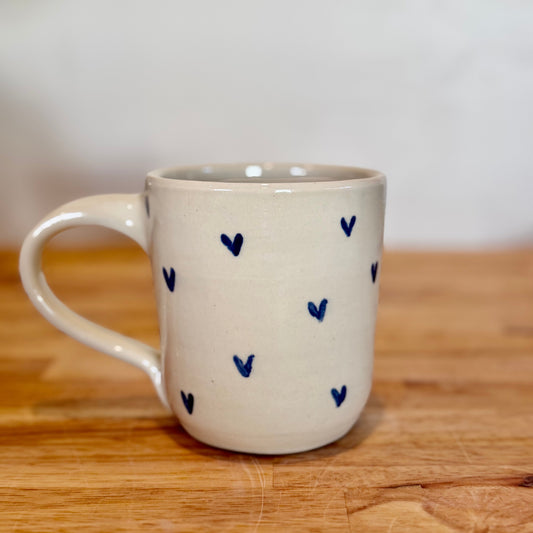 White mug with blue heart patterns on a wooden surface
