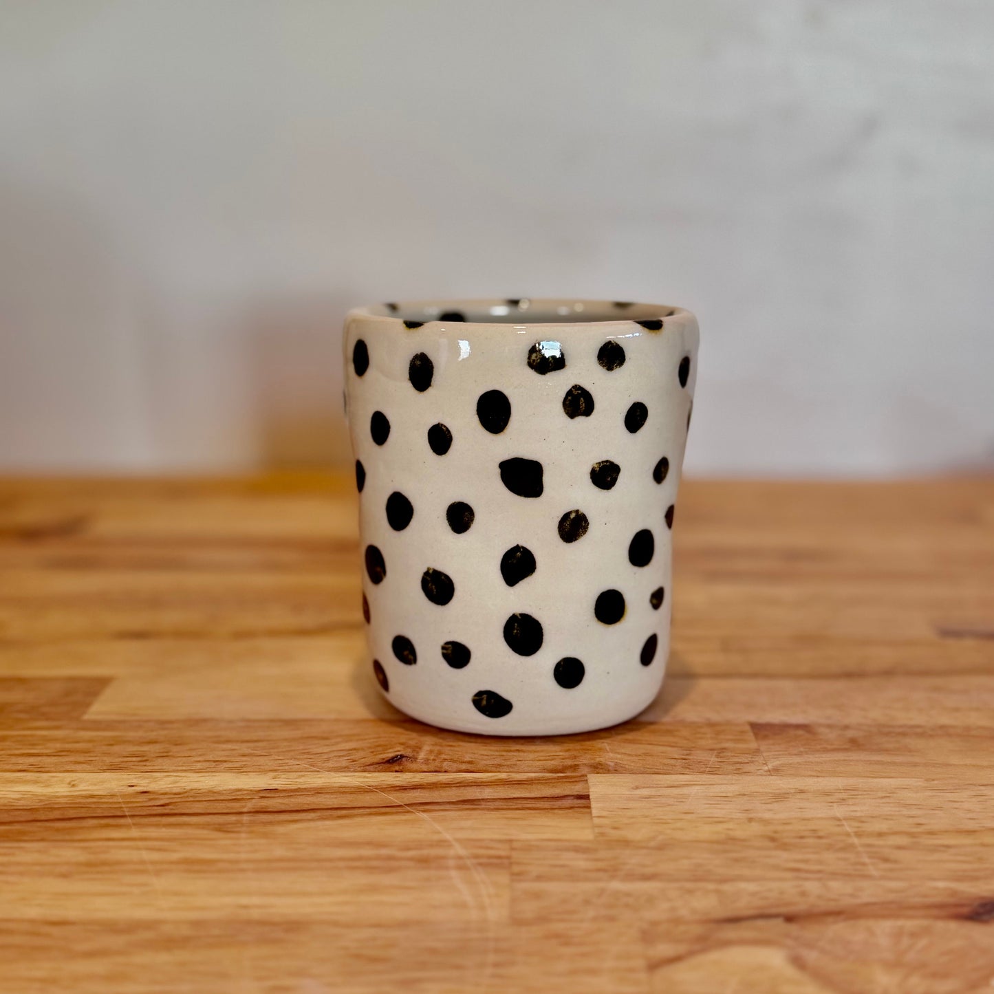 Ceramic cup with black polka dots on a wooden surface