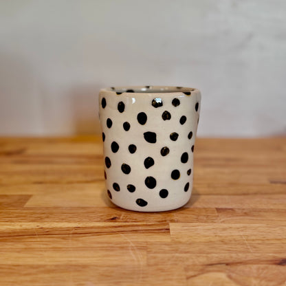 Ceramic cup with black polka dots on a wooden surface