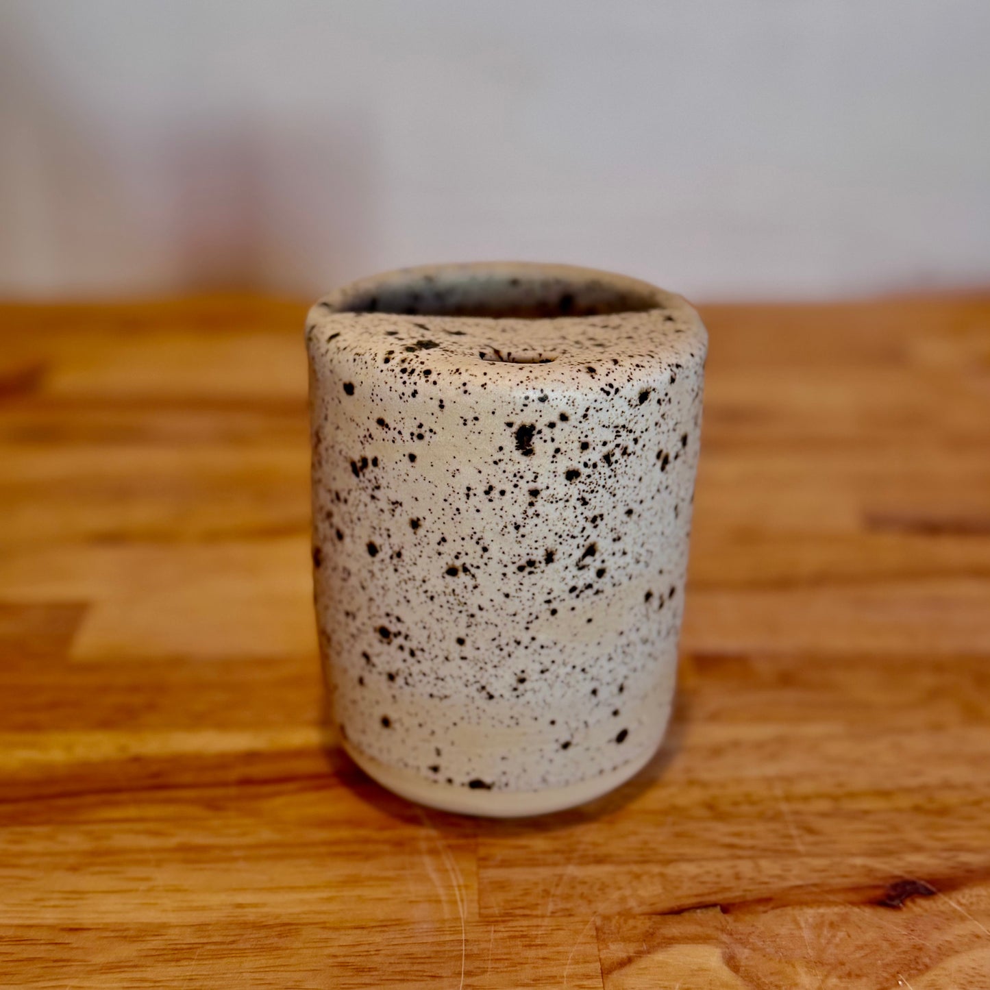Speckled ceramic cup on a wooden surface with a blurred background