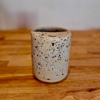 Speckled ceramic cup on a wooden surface with a blurred background