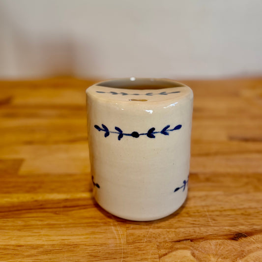 Small ceramic container with blue designs on a wooden surface